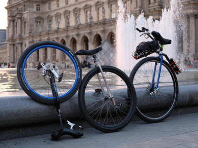 Trois monocycles posés le long d'une fontaine, au Louvre, à Paris.